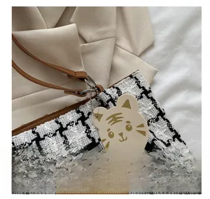 Détail d'un charme chat de dessin animé sur un sac cabas en tweed noir et blanc