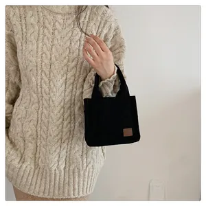 Detailansicht Mini-Tragetasche aus schwarzem Cord mit Lederpatch auf Herbststrickpullover