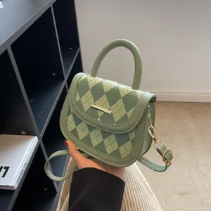 Green quilted saddle bag with gold-tone hardware and adjustable strap shown by model