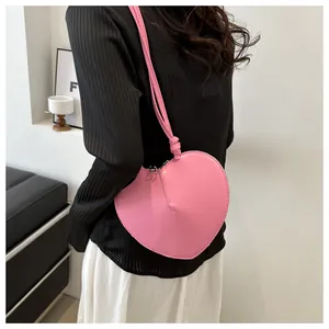 Model met een roze hartvormige schoudertas van glad PU-leer en een ritssluiting