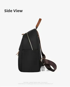 Side view of black oxford cloth backpack featuring brown leather handles and side pocket