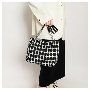 Detail of black and white plaid tweed bag with silver chain handles and leather patch