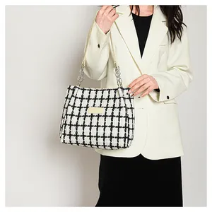 Detail of black and white tweed tote bag with leather straps and silver chain accents