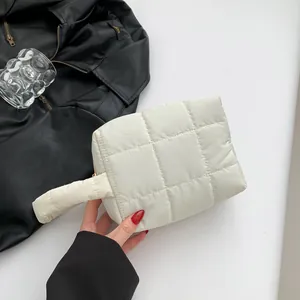 White quilted puffer handbag with padded handle and gold zipper closure for minimalist style