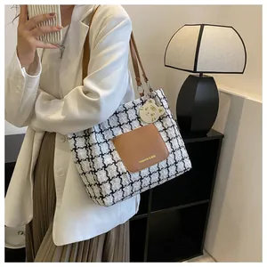 Vue détaillée du sac cabas à carreaux avec poche en cuir brun et breloque de tigre
