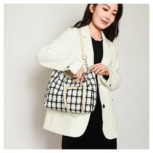 Detail of checkered tweed tote bag with beige leather straps and gold metal chain