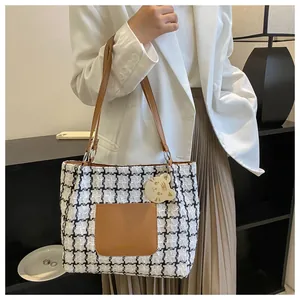 Détail du sac cabas en tweed noir et blanc avec poche en cuir marron et pendentif chat