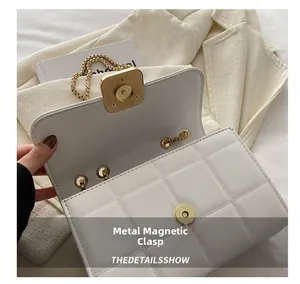 Gros plan sur le fermoir magnétique carré doré d'un sac à bandoulière matelassé blanc