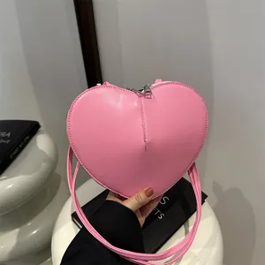 Roze hartvormige schoudertas van mat PU-leer met zilveren ritsen en lange riem