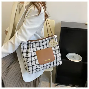 Détail du cabas en tweed à carreaux avec bordure en cuir marron et breloque chat
