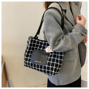 Détail du sac cabas à carreaux avec texte de mode et charme sur costume à rayures