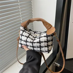 Klassieke zwart-wit geruite tweed handtas met bruine lederen handvatten en schouderriem