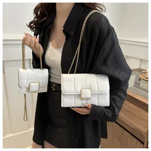 Détail du matelassage blanc et du fermoir doré sur le sac à chaîne minimaliste chic