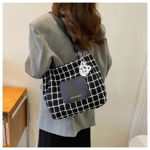 Détail du sac cabas à carreaux avec poche en cuir, breloque chat et texte imprimé