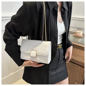 Détail du sac bandoulière blanc matelassé avec boucle dorée et chaîne porté par un mannequin