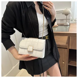 Détail du sac matelassé blanc avec chaîne, fermoir doré et texture cuir sur une table