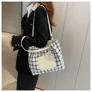 Détail d'un sac cabas en tweed noir et blanc avec anses en cuir et breloque chat