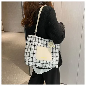 Détail du cabas à carreaux avec poche avant blanche et breloque chat jaune sur un modèle