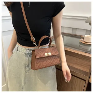 Detail of woven texture and golden buckle on brown square crossbody leather bag