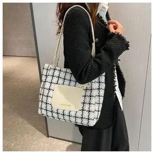 Gros plan d'un cabas en tweed à carreaux noir et blanc avec poche avant en similicuir