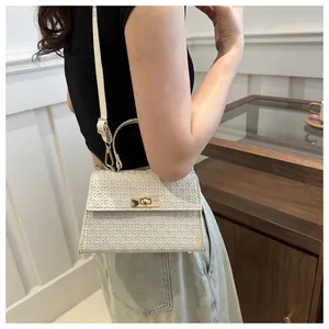Detailed view of beige woven texture handbag with golden metal twist lock and top handle