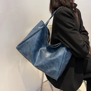 Large vintage navy blue faux leather tote bag for women shown on shoulder in daily use
