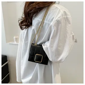 Gros plan du mini sac matelassé noir avec boucle dorée carrée et bandoulière chaîne