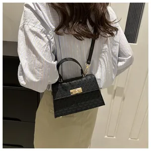 Detail view of a black geometric woven crossbody bag with gold hardware on a model