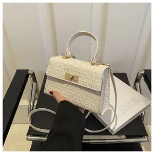 Detail of white crossbody bag with woven texture, metal swivel lock and round top handle