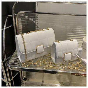 Gros plan de sacs matelassés blancs avec boucles dorées sur une étagère d'étalage