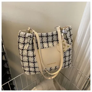 Détail du sac cabas à carreaux avec poche en cuir beige et breloque tigre en panier
