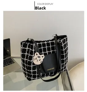 Détail du cabas en tweed à carreaux avec poche en cuir et breloque chat blanc