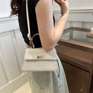 Elegant ivory woven crossbody bag with gold hardware shown on a model in a minimal setting