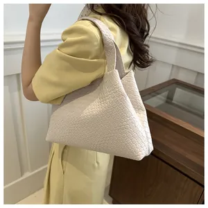 Detalle de bolso shopper trenzado crema con silueta triangular y textura de cuadros