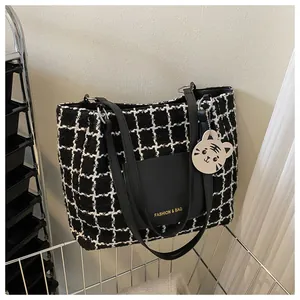 Détail du sac cabas en tweed noir et blanc avec poche en cuir et breloque tigre