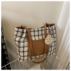 Détail du sac cabas à carreaux avec poche en cuir marron et pendentif chat mignon