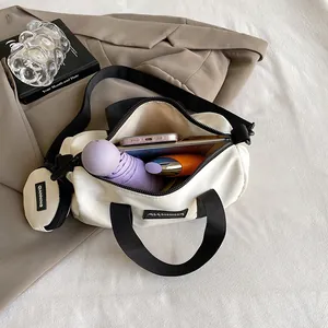 Chic white nylon Boston bag with black handles and small coin pouch in a stylish setup