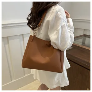 Detail of caramel brown tote bag with lychee texture and golden metal ring hardware