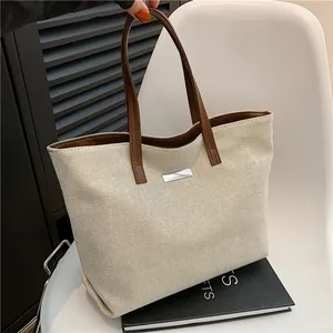 Minimalist canvas tote bag with brown leather handles and silver metal hardware detail