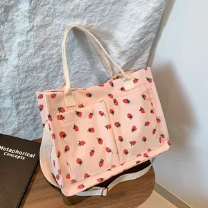 Pink corduroy strawberry tote bag with two front pockets and adjustable shoulder strap