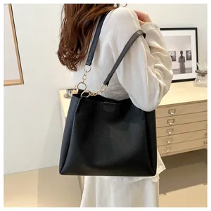 Detail of black pebbled leather tote bag with elegant gold chain shoulder strap accents