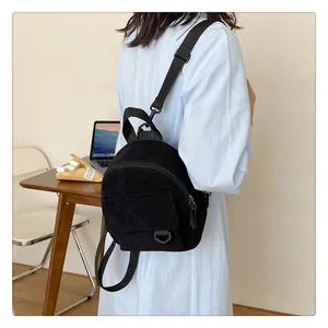 Primer plano de una mini mochila de pana negra en un modelo en un entorno de estilo de vida
