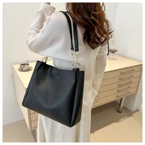 Detail view of black pebble leather tote bag with gold chain accents and sturdy handles