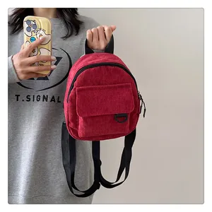 Detalle de la mini mochila de pana roja sostenida por una modelo para ver el tamaño