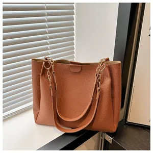 Detail of caramel brown faux leather tote with lychee grain and gold chain strap