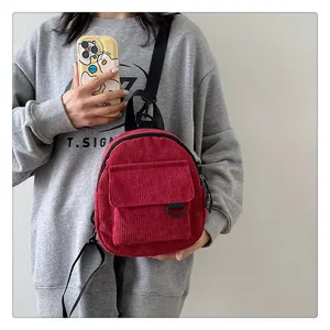 Primer plano detallado de una mini mochila de pana roja con correas de nailon negro