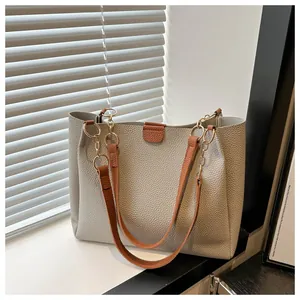 Close-up of gray lychee leather tote bag with brown straps and golden chain details