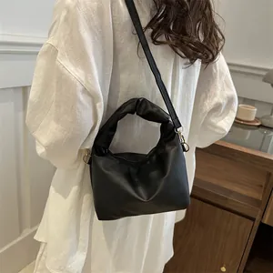 Minimalist black pleated handbag with shoulder strap and cloud-like design