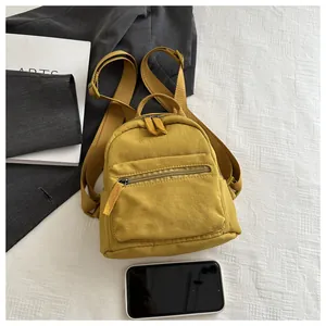 Miniature ginger yellow canvas backpack with smartphone reference on a minimalist background
