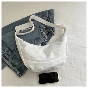 Platte lay van een witte halve maan schoudertas met denim jas en lifestyle accessoires